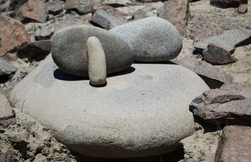 Piedras de formas redondeadas y una pieza alargada sobre una superficie plana de piedra.