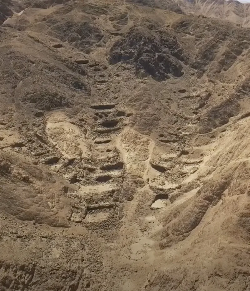 Recintos y muros de piedra sobre un terreno árido y accidentado.