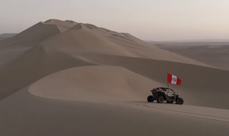 Dunas de arena y un vehículo arenero con bandera peruana en Usaka.