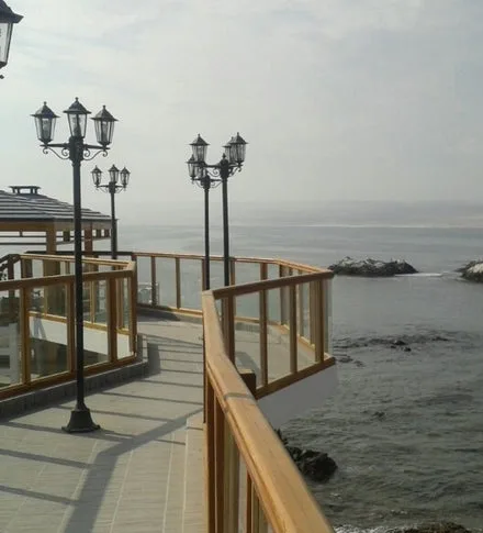 Paseo con barandas de madera y farolas junto al mar.