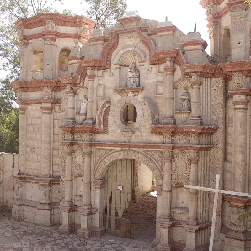 Fachada ornamentada de un templo con elementos de ladrillo y un acceso con rejas de madera.